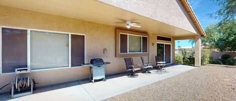 A house with a covered patio, a ceiling fan, and a grill.