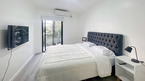 A modern bedroom with a large bed, a TV mounted on the wall, and a sliding glass door to the outside. - Charming Apartment in Recoleta 4 Paxa (Buenos Aires)