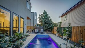 Una casa moderna con piscina, valla de madera y plantas en macetas.