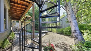 A spiral staircase leading to a covered porch with hanging flower baskets. - Walk to Cafes! Storybook-Style Fairbanks Studio (Fairbanks)