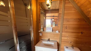 Interior em madeira com uma pia branca, um espelho e um vaso sanitário.