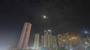 A nighttime cityscape with high-rise buildings and a visible moon. - 3bhk fully furnished highrise apartment in a luxerious complex with lake view (Kolkata)