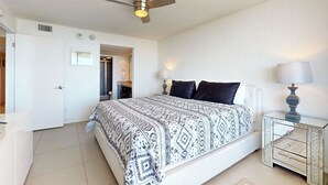 Ein Schlafzimmer mit Bett, Nachttischen, Deckenventilator und einer Tür.