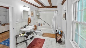 Ein Badezimmer mit Badewanne, Toilette, Waschbecken und Holzbalken an der Decke.