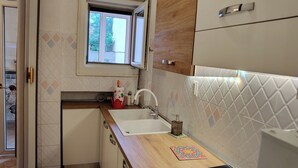 Una cocina moderna con ventana, armarios blancos, un fregadero y salpicadero de azulejos.