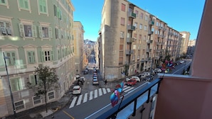Vista de una calle con edificios, un paso de peatones y coches aparcados.
