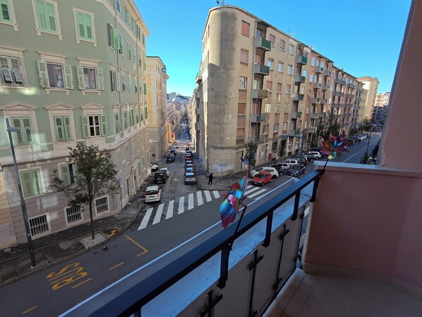 A street view with buildings, a pedestrian crossing, and parked cars.