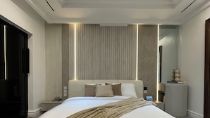 A modern bedroom with a large bed, bedside tables, a nightstand, and a mirror. - Two Bedroom Luxury Apartment in Maitama, Abuja (Abuja)