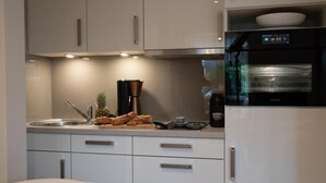 A modern kitchen with white cabinets, a built-in oven, and a coffee maker. - Facilities & Highlights (Timmendorfer Strand)