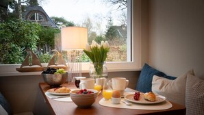 A breakfast table with fruits, pastries, and drinks, a vase with flowers, and a lamp. - Facilities & Highlights (Timmendorfer Strand)