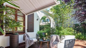 A patio with wicker furniture, a potted plant, and a view of a garden. - Facilities & Highlights (Timmendorfer Strand)
