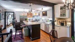 A modern kitchen with a central island, stainless steel appliances, and pendant lighting. - Hideaway Hill lux downtown garden cottage & hottub (Waynesville)