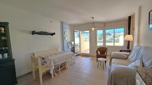 Ein Wohnzimmer mit einer Couch, einem Esstisch, einem Stuhl, einem Ventilator und einem Fenster mit Blick.