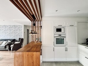 A modern kitchen with white cabinets, a wooden island, and a built-in oven. - Modern Apartment in the Heart of Roses, Near the Beach (Roses)
