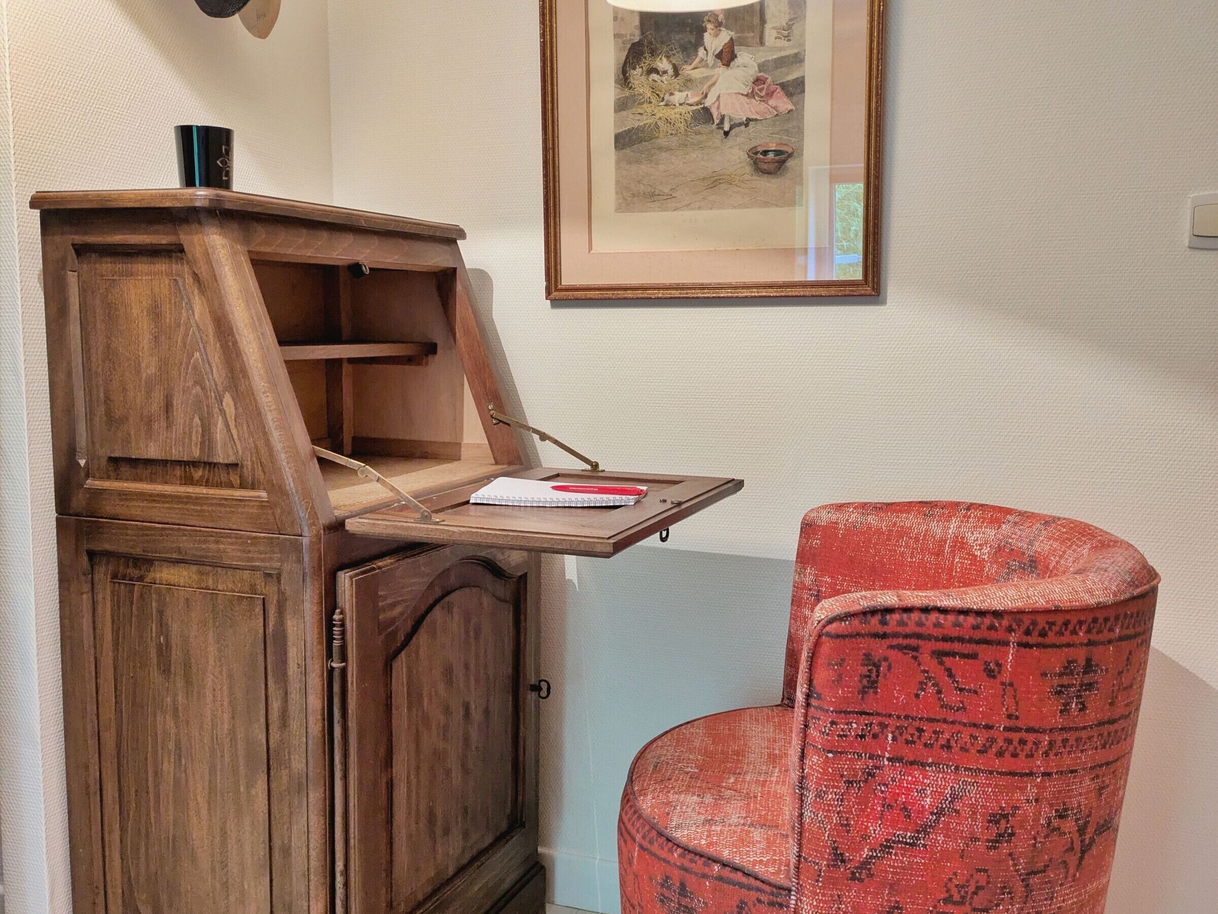 Un escritorio de madera con una mesita y una silla roja con estampado.