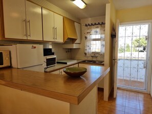 A kitchen with a wooden countertop, a bowl, a refrigerator, a microwave, and a sink. - 3-bedroom apartment with terrace near the beach (L'Escala)