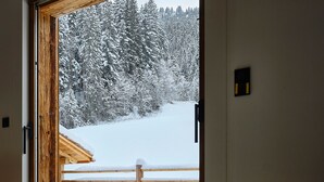 Eine Holztür, die zu einem verschneiten Außenbereich mit einem Holzzaun führt.