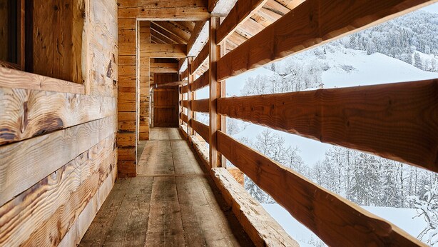 Ein Holzkorridor mit Blick auf eine verschneite Landschaft.