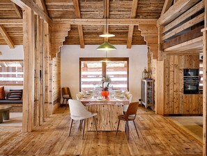 A rustic wooden interior with a dining table set for six, wooden beams on the ceiling, and built-in appliances. - Spacious chalet in Grand-Bornand with parking and pets allowed (Le Grand-Bornand)