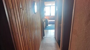 Ein schmaler Korridor mit Holzwandverkleidung an einer Seite und Fliesenboden.