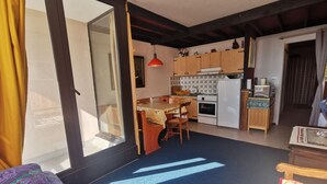 Eine kleine Küche mit Holzausstattung, einem Esstisch und einem Kühlschrank.