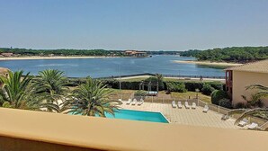 Et resort med swimmingpool, liggestole og udsigt over en flod og strand.