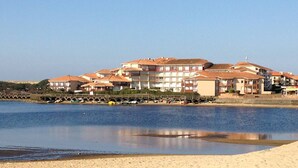 Et kysthotel med flere bygninger, en sandstrand og et roligt hav.