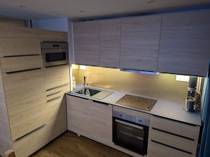 A modern kitchen with wooden cabinets, a built-in oven, a sink, and a coffee machine. - 2-room Apt, Plagne Centre, 5 ppl, slope view (La Plagne)