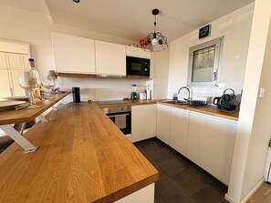 A modern kitchen with white cabinets, a wooden countertop, a microwave, a sink, and a kettle. - T3 Apartment in Bormes-les-Mimosas - Near beaches and amenities (Bormes-les-Mimosas)