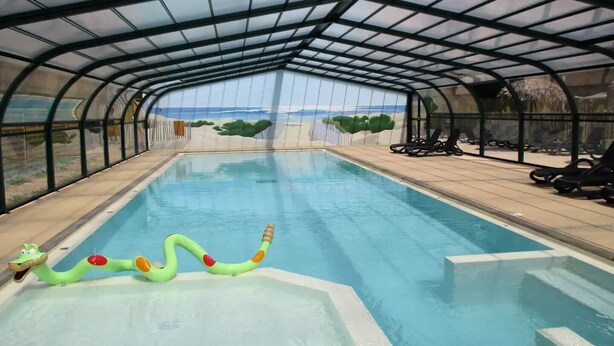 An indoor swimming pool with a glass ceiling, clear pool water, and lounge chairs along the sides. - Family Mobile Home: 3 Rooms, Sleeps 4 (SAINT-HILAIRE-DE-RIEZ)
