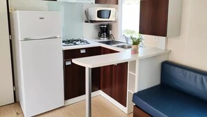 A compact kitchen with a refrigerator, stove, microwave, and sink. - Family Mobile Home: 3 Rooms, Sleeps 4 (SAINT-HILAIRE-DE-RIEZ)