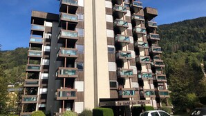 Een meerlaags gebouw met balkons, een bord waarop 'Hotel' staat en een bergachtige achtergrond.