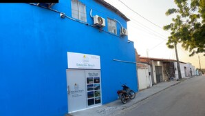 Un bâtiment bleu avec une enseigne indiquant « Emocoes Beach » et une moto garée devant.