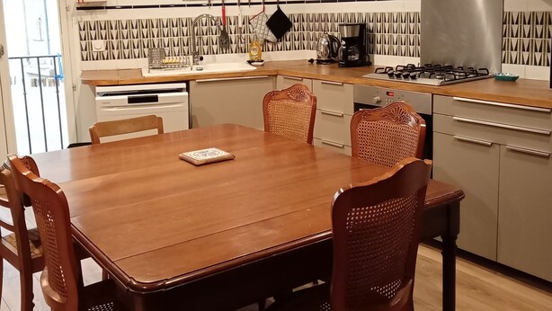 Uma cozinha moderna com mesa e cadeiras de madeira, fogão a gás e cafeteira.