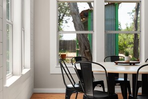 A dining area with a table and chairs, a window with a view of trees and a building, and a potted plant on the table. - Tranquil 4BR Retreat on 2 Acres w/ Boat Dock – Lago Vista (Lago Vista)