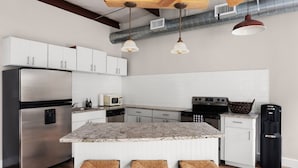 A modern kitchen with a stainless steel refrigerator, white cabinets, a marble island, and a black trash can. - Tranquil 4BR Retreat on 2 Acres w/ Boat Dock – Lago Vista (Lago Vista)