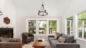 A living room with a fireplace, two sofas, a coffee table, and large windows. - Tranquil 4BR Retreat on 2 Acres w/ Boat Dock – Lago Vista (Lago Vista)