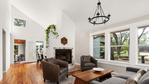 A spacious living room with a fireplace, large windows, and a high ceiling. - Tranquil 4BR Retreat on 2 Acres w/ Boat Dock – Lago Vista (Lago Vista)