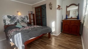 Ein Schlafzimmer mit einem hölzernen Bett, einem Kleiderschrank und einem Spiegel.