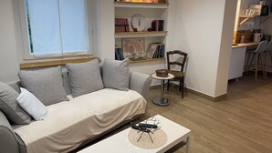 Ein Wohnzimmer mit einer Couch, einem Couchtisch, einem Bücherregal und einem Essbereich mit Stühlen.