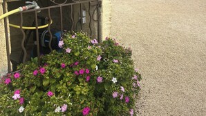 Ein Steinhaus mit einem hufeisenförmigen Schild, einem Kieshof und einem Blumenbeet mit rosa und weißen Blumen.