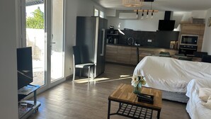 Ein modernes Schlafzimmer mit einem Bett, einem Holztisch und einem Stuhl. Es gibt eine Küchenzeile mit Spüle und Schränken.