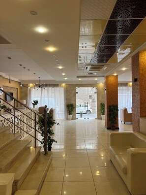 A spacious lobby with a staircase, a reception desk, and a view of the street. - Hôtel kssar  (Oran)
