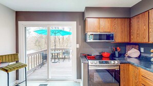 Una cocina con armarios de madera, microondas, estufa y comedor con banco y sillas.