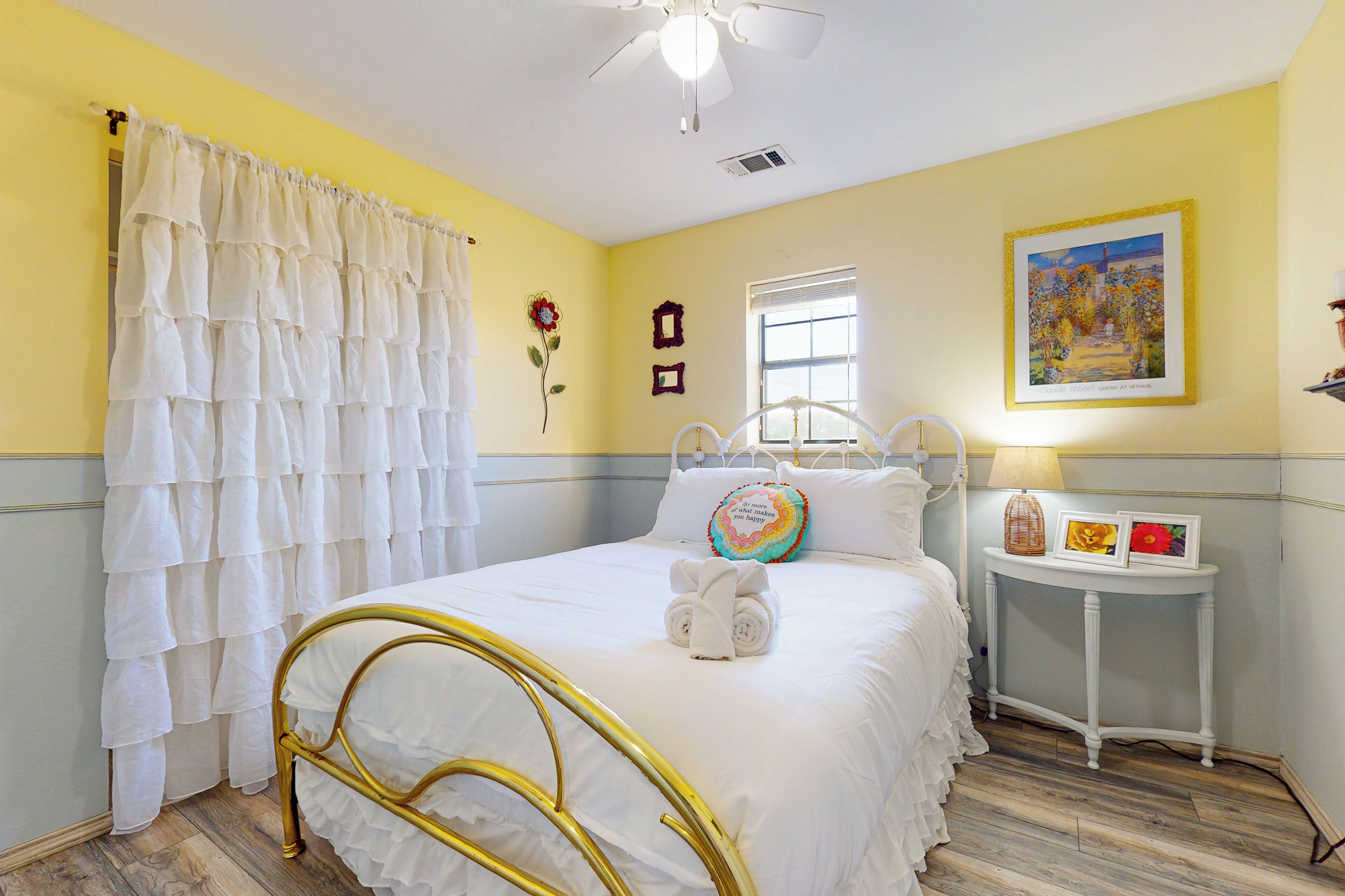 A bedroom with a bed, a bedside table, a window, and a ceiling fan.