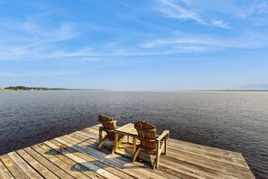 A wooden dock with two Adirondack chairs facing a calm body of water under a clear sky. - Pool, Dock! Group Getaway on Chowan River (Merry Hill)