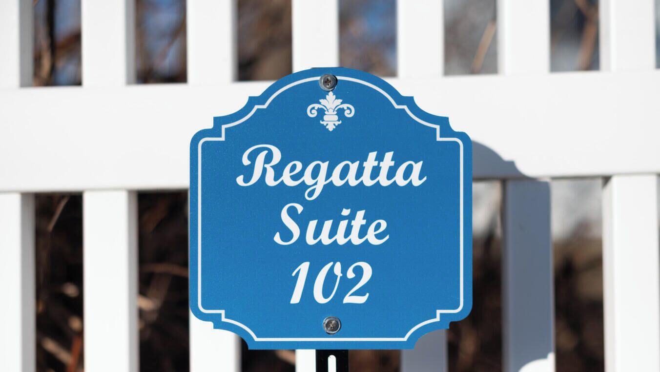 A sign for "Regatta Suite 102" with a decorative border and a small emblem at the top.