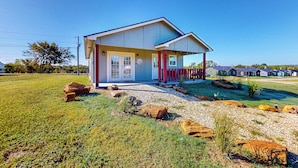 A single-story house with a front porch, a garage, and a well-maintained lawn with rocks and plants. - Steps to Lake Eufaula: Home w/ Fire Pit & BBQ (Eufaula)