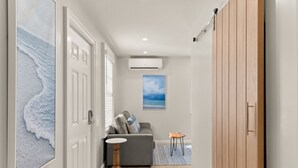A hallway with a grey sofa, a small round table, and a wooden wardrobe.