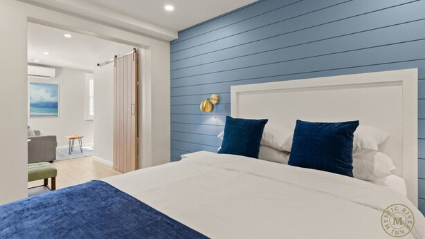 A bedroom with a large bed, a blue wall, and a white headboard.